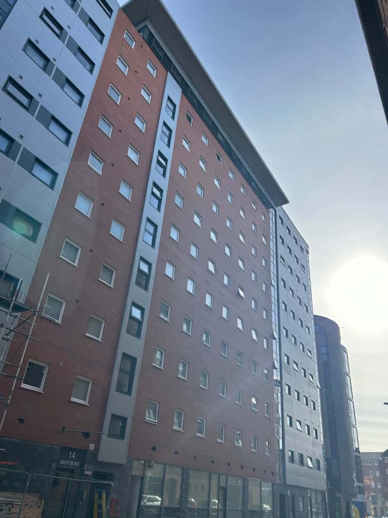 Tall red brick building with metallic cladding