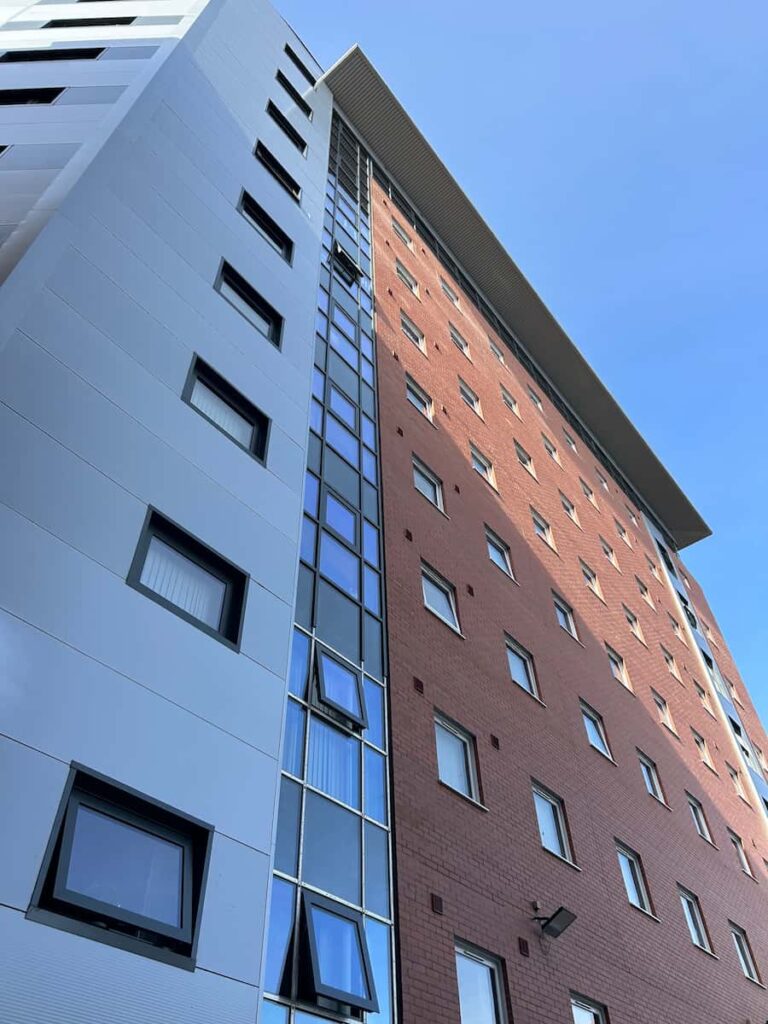 Tall red brick building with metallic cladding