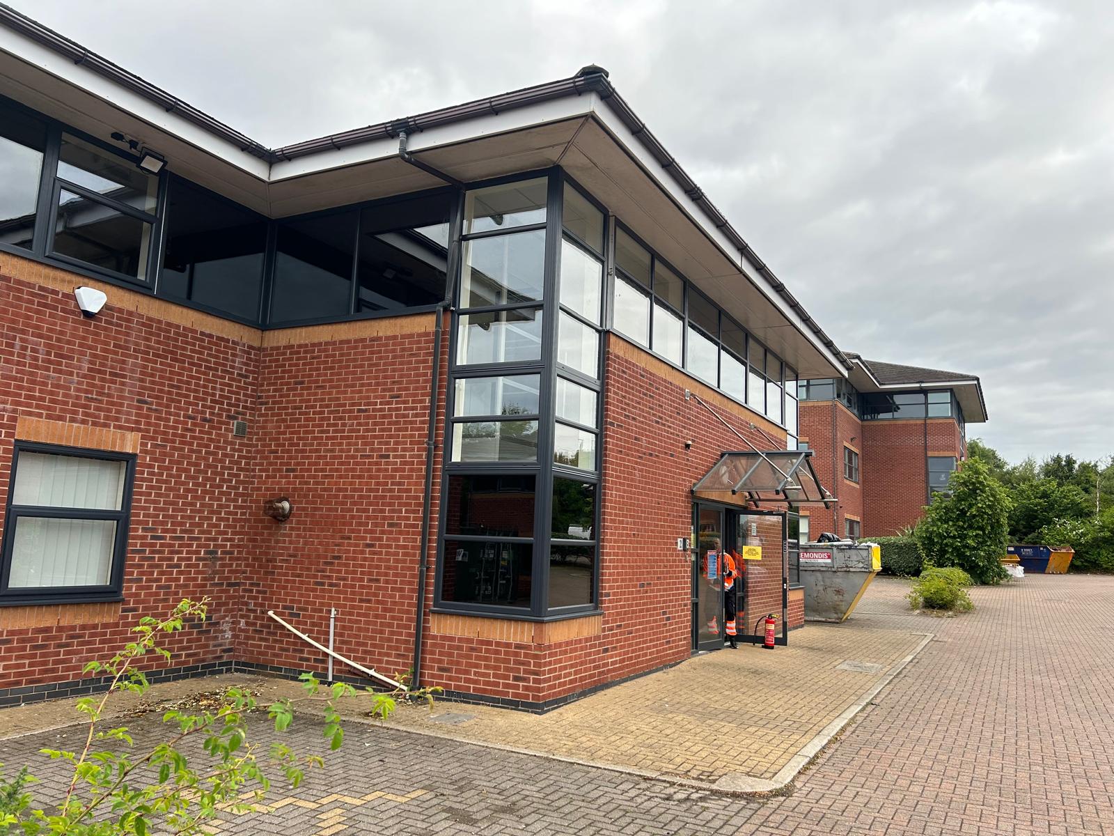 Red brick building with lots of glass windows incorporated below the roofline